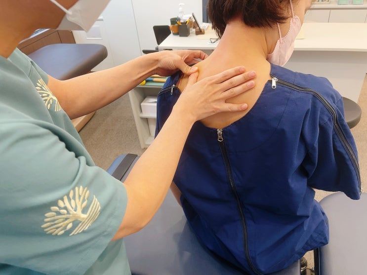 앉은 환자의 목을 진찰하는 모습